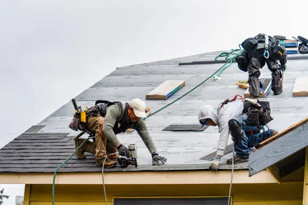 Insurance Claim 3 Roofing crew installing shingles on a roof