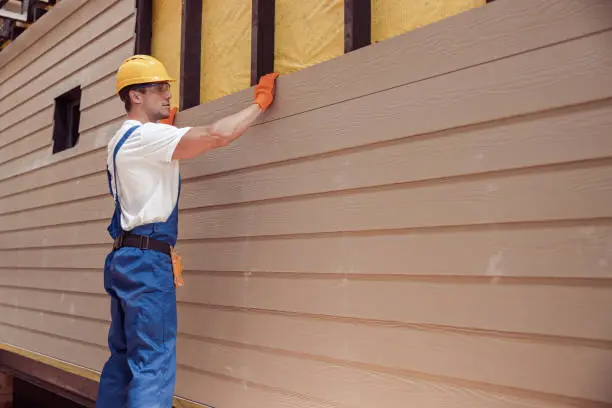 Home Builders Greenville, NC 8 Worker installing siding on a house