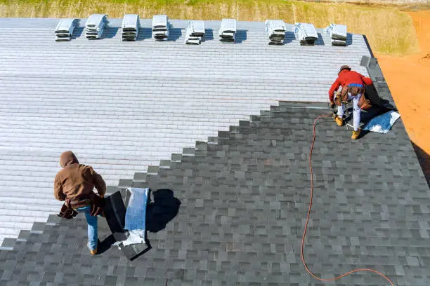 Insurance Claim 5 Roofers installing shingles on a large roof