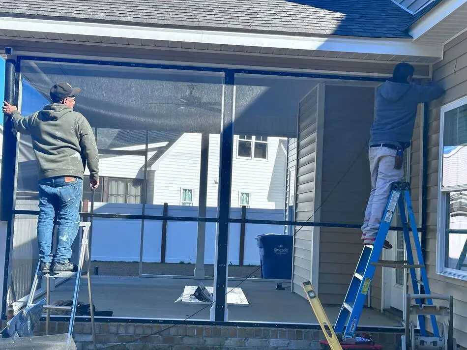 About Us 6 Workers installing screen panels on a porch addition