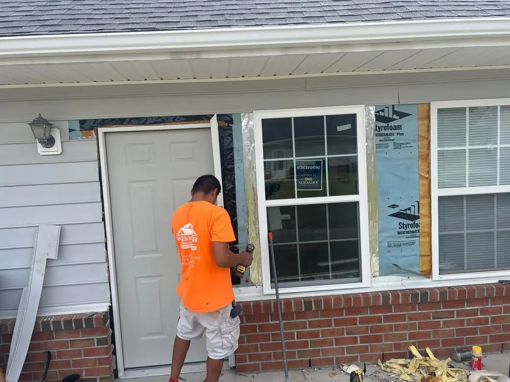 Home 8 Contractor in an orange shirt installing new windows and a door
